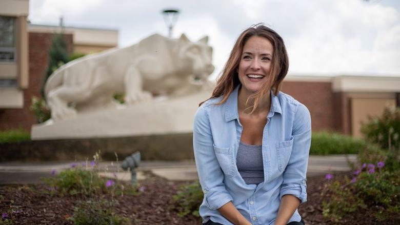 Woman sits in front of Nittany Lion Shrine